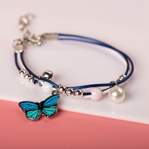 Pulsera con colgante de mariposa azul con perlas blancas sobre fondo blanco y rosa