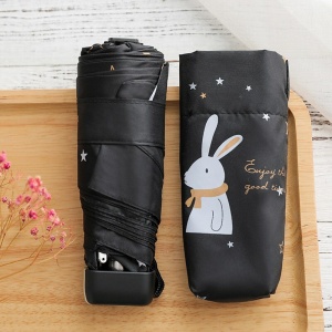 Mini paraguas de bolsillo para niños con conejo blanco sobre un paraguas negro en una mesa de madera