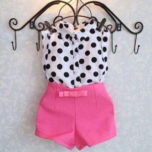 Pantalones cortos rosas con camisa blanca estampada con lunares negros en una percha negra