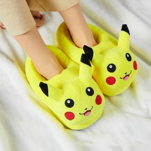 Pantuflas infantiles con forma de Pikachu de felpa deslizadas sobre los pies con una manta blanca
