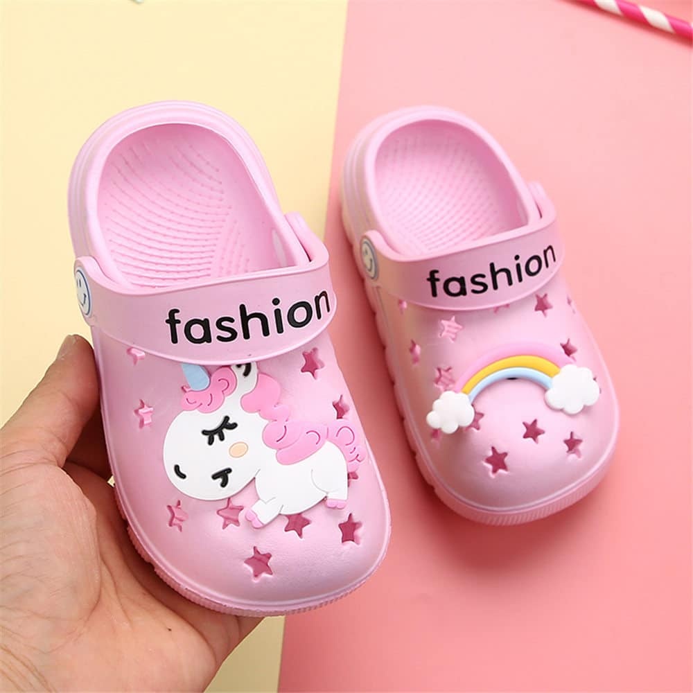 Divertidas zapatillas infantiles de unicornio en una mano con diseño colorido
