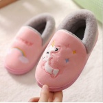 Zapatillas de bebé unicornio rosas y grises sobre una alfombra blanca