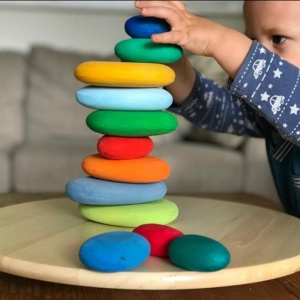 juguetes apilables de piedras de colores para niños en un plato de madera