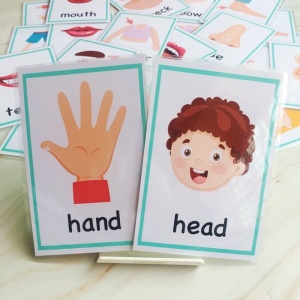 Juego de cartas para bebés con la mano y la cabeza y otras cartas sobre una cama