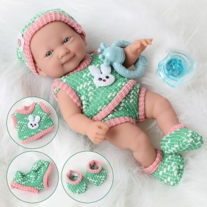 Muñeca blanda para recién nacidos con ropa verde y rosa sobre una bata blanca