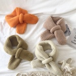 Cálida bufanda de lana para niños sobre una cama blanca con abrigo
