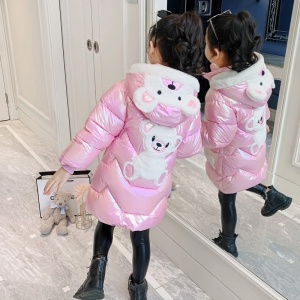 Chaqueta larga y brillante con capucha de oso para niñas en rosa con oso en la capucha y en la espalda sobre una niña delante de un espejo