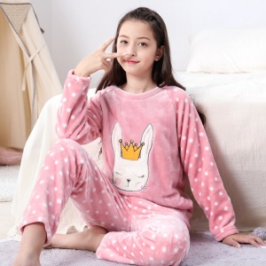 Una niña con un pijama polar con estampado de conejitos blancos en la cama