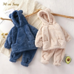 Pijama de forro polar con capucha y orejas de oso para niños en beige y azul sobre una alfombra blanca