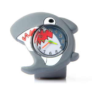 Un reloj infantil de plástico con un simpático tiburón, con esfera de cristal en el centro, manecillas de colores en el interior y los dientes del tiburón impresos.