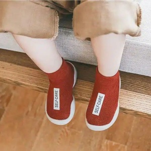 vemos las piernas de un niño sentado que lleva calcetines rojos con una etiqueta blanca