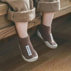 vemos las piernas de un niño sentado que lleva calcetines marrones con una etiqueta blanca