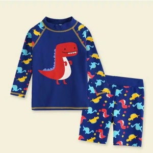 un conjunto de bañador para niños, pantalón corto y camiseta azul con motivos de dinosaurios sobre fondo beige