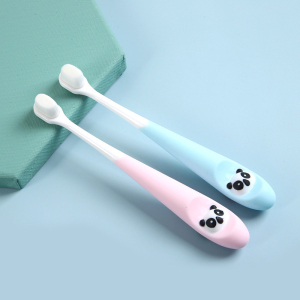 2 cepillos de dientes para bebés en rosa y azul colocados sobre un soporte verde